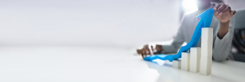 Business professional analyzing a 3D bar graph with an upward arrow, representing sales growth and business acceleration.